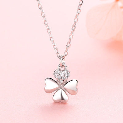 Silver four-leaf clover pendant necklace on a pink background