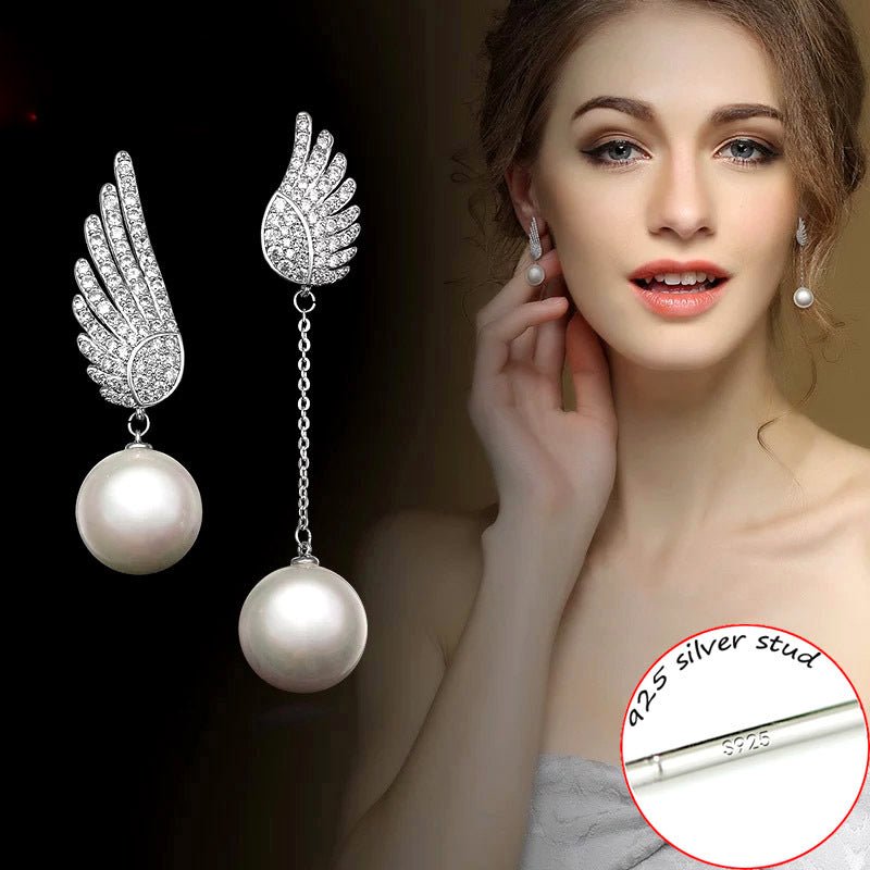 Pearl earrings with silver wings on a dark background, shown on a model wearing one earring.