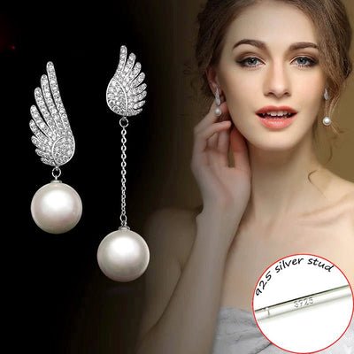 Pearl earrings with silver wings on a dark background, shown on a model wearing one earring.