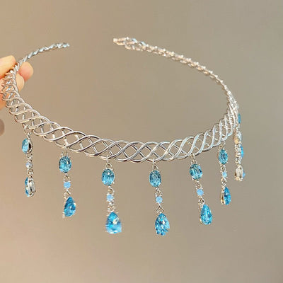 Silver tiara with blue gemstones on a neutral background