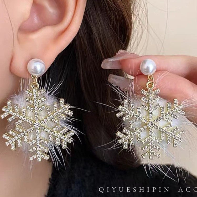 Snowflake earrings with pearls and feathers worn by a person