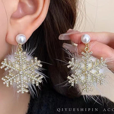 Snowflake earrings with pearls and feathers worn by a person