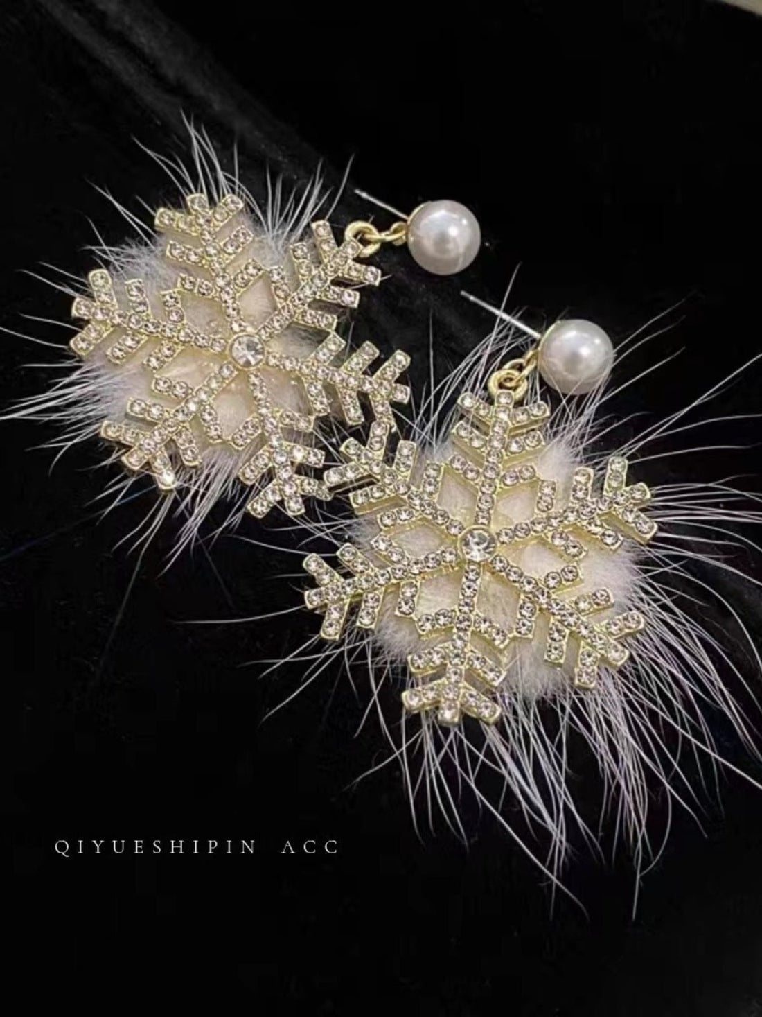 Snowflake-shaped earrings with pearls and feathers on a black background