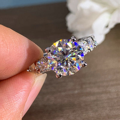 Diamond ring held between fingers with a blurred background