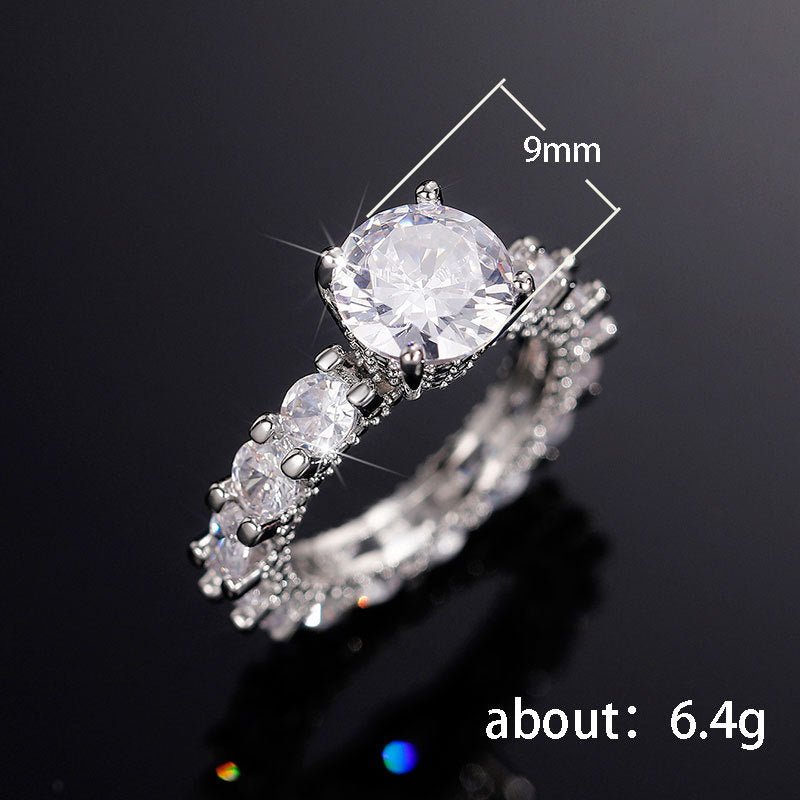 Silver ring with a large central gemstone and smaller stones on a black background