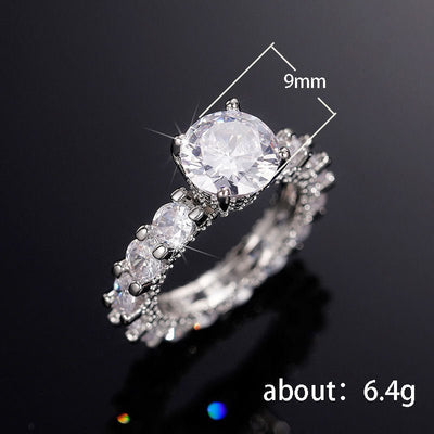 Silver ring with a large central gemstone and smaller stones on a black background