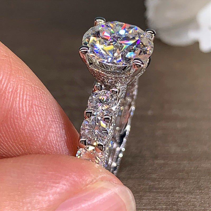 Diamond ring held between fingers against a neutral background