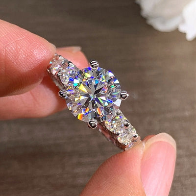 Diamond ring held between fingers against a neutral background
