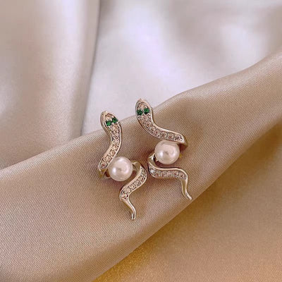 Pair of decorative earrings with pearls on a beige fabric background