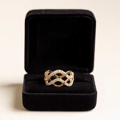 Gold ring with diamond accents in a black jewelry box on a light background