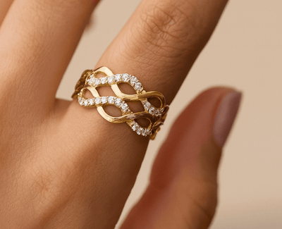 Gold ring with diamonds on a finger against a beige background