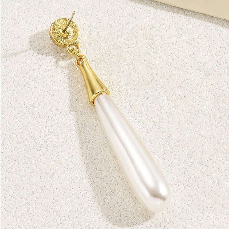 Pearl earring with gold cap on a textured white surface