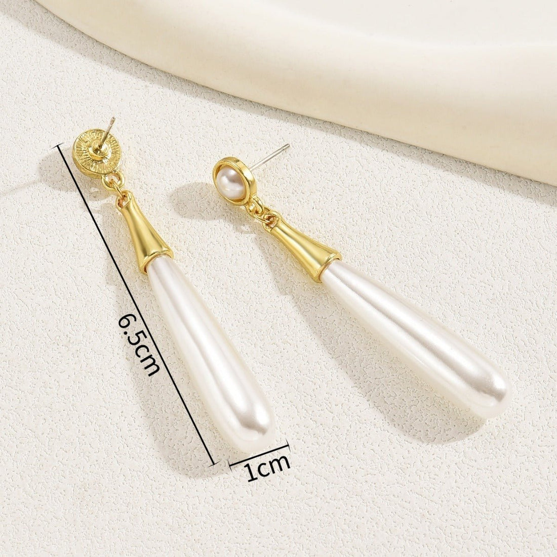 Pearl earrings with gold accents on a white surface, showing measurements.