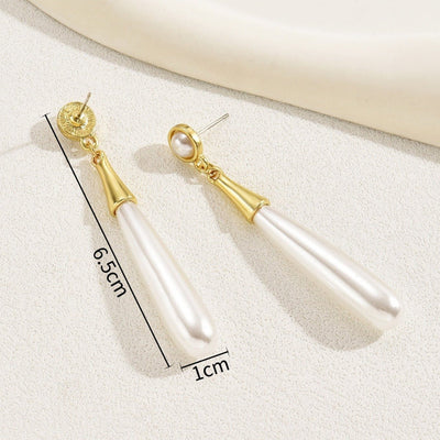 Pearl earrings with gold accents on a white surface, showing measurements.