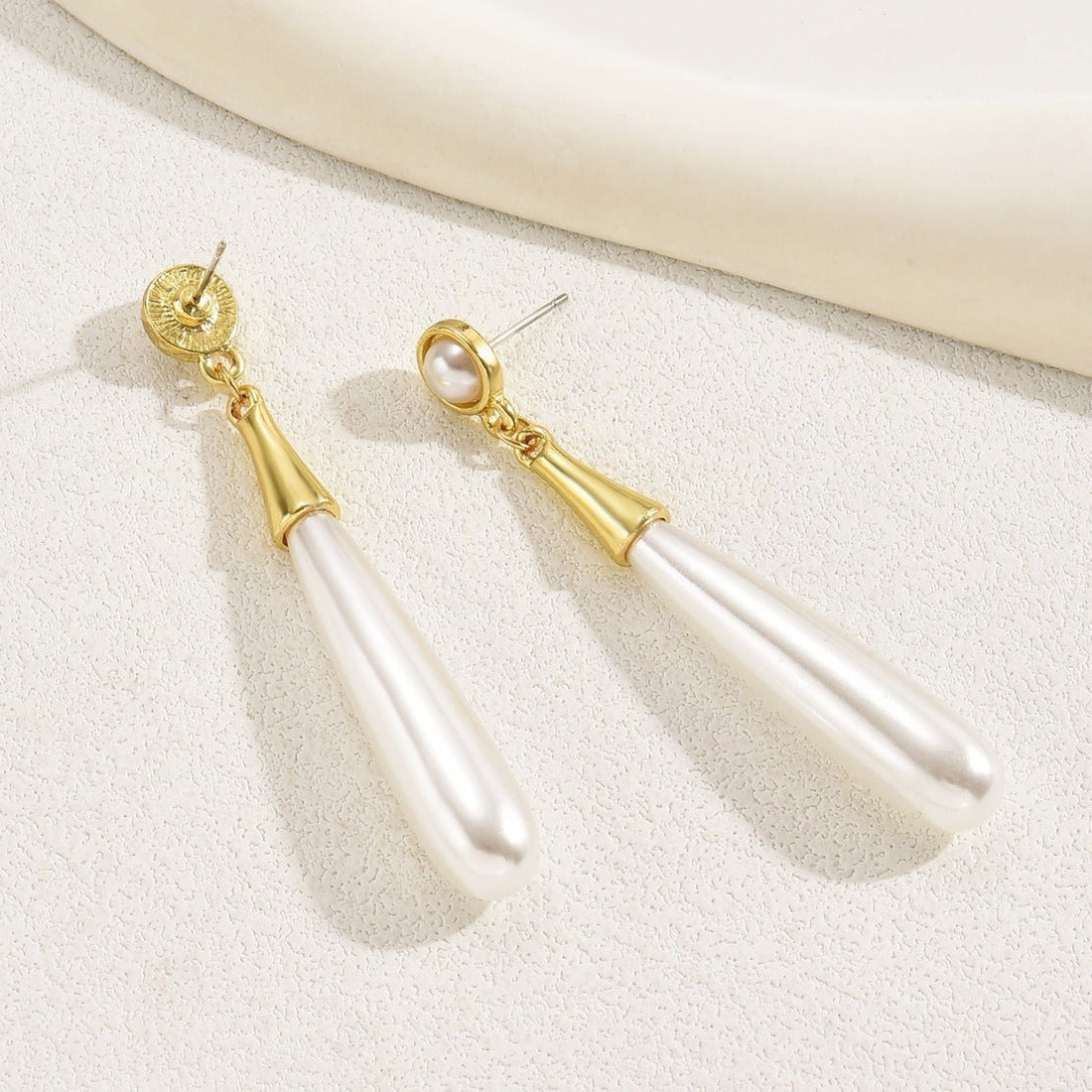 Pearl earrings with gold accents on a light background