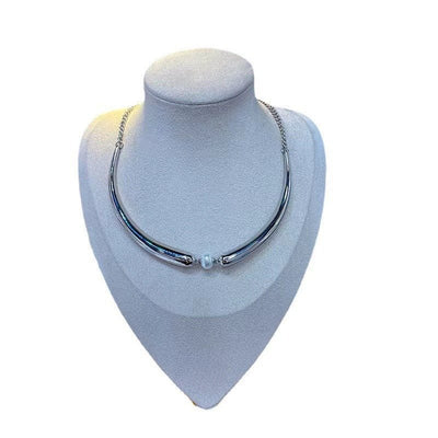 Silver necklace on a gray bust against a white background