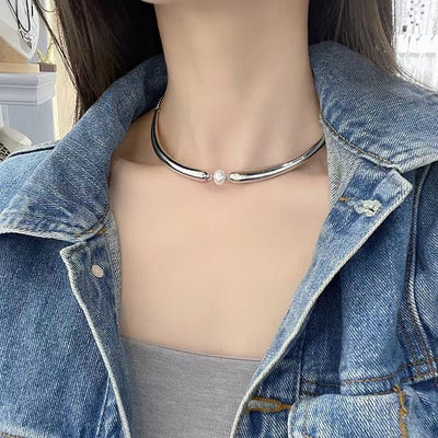 Mannequin wearing a denim jacket with a silver necklace featuring a pearl.